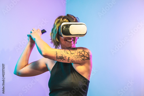 Cool Spanish girl wearing virtual reality glasses standing in a crazy position holding the remoter photo