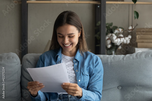 Fotografie Close up smiling woman reading good news in letter, holding paper sheet in hands
