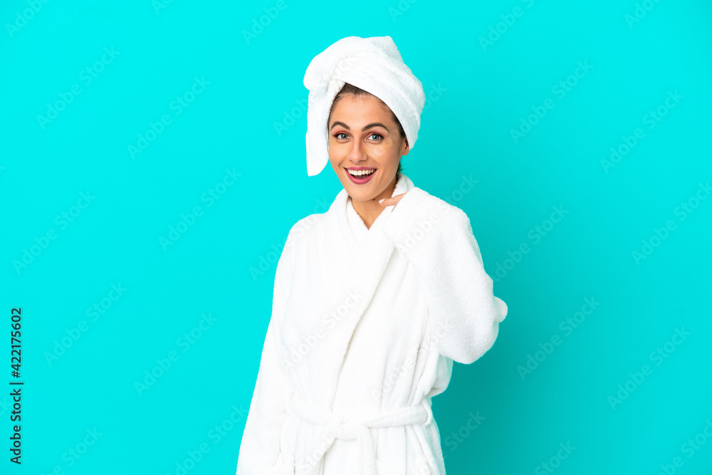 Young woman in a bathrobe over isolated blue background with surprise facial expression Young woman in a bathrobe over isolated blue background with surprise facial expression