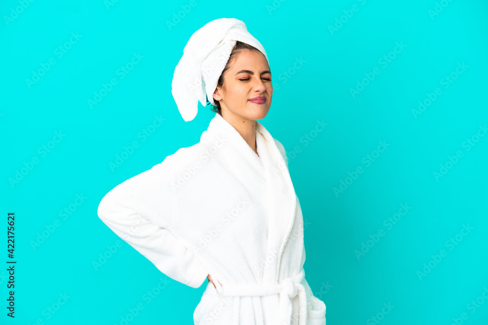 Young woman in a bathrobe over isolated blue background suffering from backache for having made an effort Young woman in a bathrobe over isolated blue background suffering from backache for having made an effort