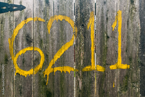 Yellow painted numbers on a wooden fence