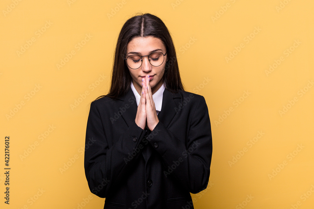 Young Indian business woman isolated on yellow background holding hands in pray near mouth, feels confident. Young Indian business woman isolated on yellow background holding hands in pray near mouth, feels confident.