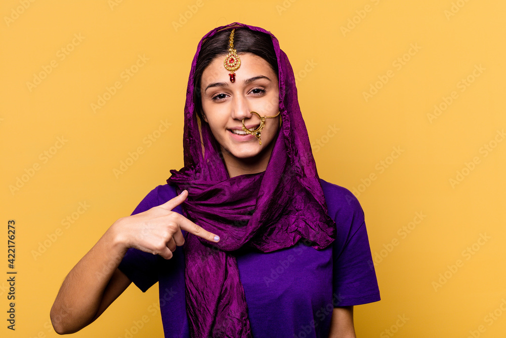 Young Indian woman wearing a traditional sari clothes isolated on yellow background person pointing by hand to a shirt copy space, proud and confident Young Indian woman wearing a traditional sari clothes isolated on yellow background person pointing by hand to a shirt copy space, proud and confident