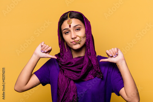 Young Indian woman wearing a traditional sari clothes isolated on yellow background feels proud and self confident, example to follow. © Asier