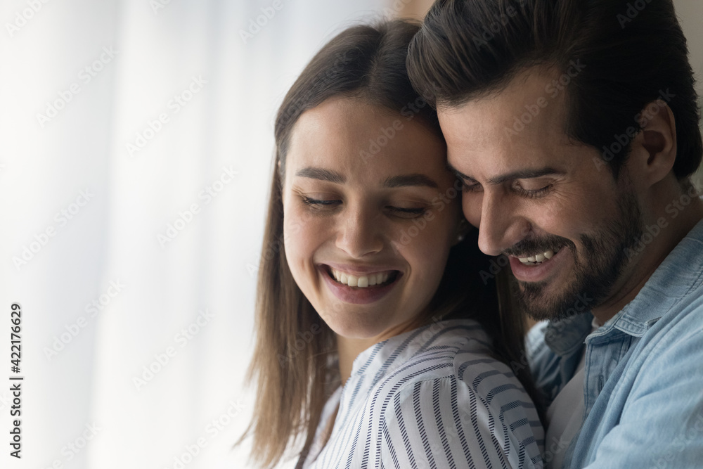 Close up smiling woman and man, young couple enjoying tender moment, hugging, standing at home, happy wife and husband expressing love and care, spending free time together, romantic date concept Close up smiling woman and man, young couple enjoying tender moment, hugging, standing at home, happy wife and husband expressing love and care, spending free time together, romantic date concept