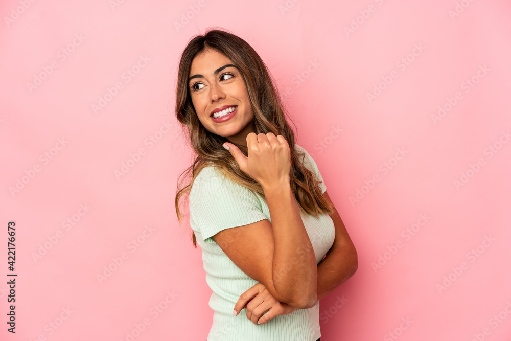 Young caucasian woman isolated points with thumb finger away, laughing and carefree. Young caucasian woman isolated points with thumb finger away, laughing and carefree.