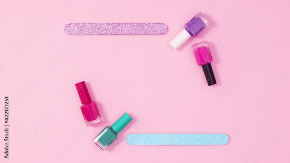 Copy space frame made of nail polish bottles and files on bright pink background. Stop motion Copy space frame made of nail polish bottles and files on bright pink background. Stop motion