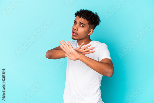 Young african american curly man isolated on blue doing a denial gesture