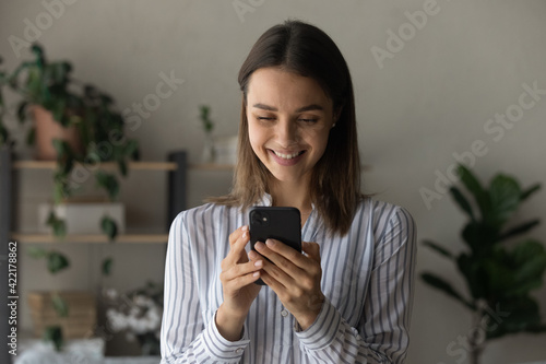 Head shot close up smiling woman looking at smartphone screen, reading good news in message or social network, satisfied customer shopping online, browsing apps, having fun with mobile device