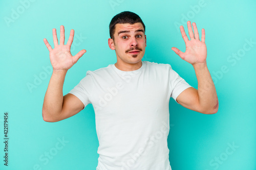 Young caucasian man isolated on blue background screaming to the sky, looking up, frustrated.