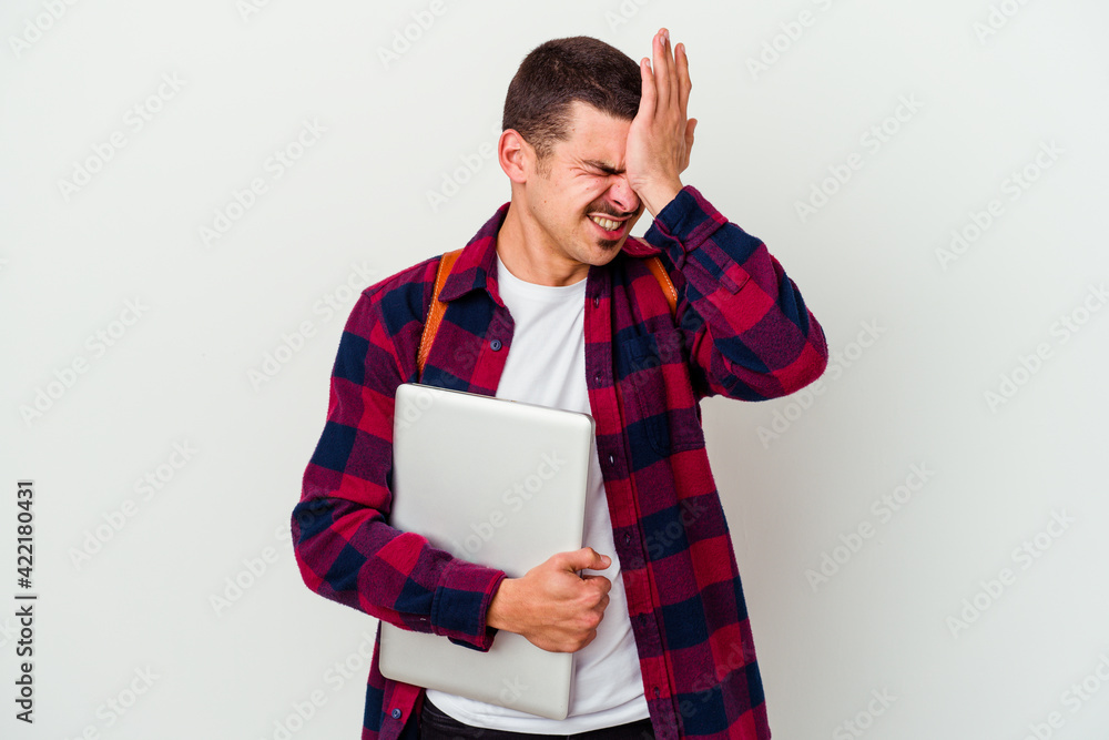 Young caucasian student man holding a laptop isolated on white background forgetting something, slapping forehead with palm and closing eyes. Young caucasian student man holding a laptop isolated on white background forgetting something, slapping forehead with palm and closing eyes.