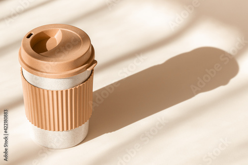 Reusable cup, biodegradable travel plastic coffee mug for take away. Sustainable bamboo eco friendly cup on natural shadow beige background. Zero waste, sustainability concept. Ban single use plastic photo