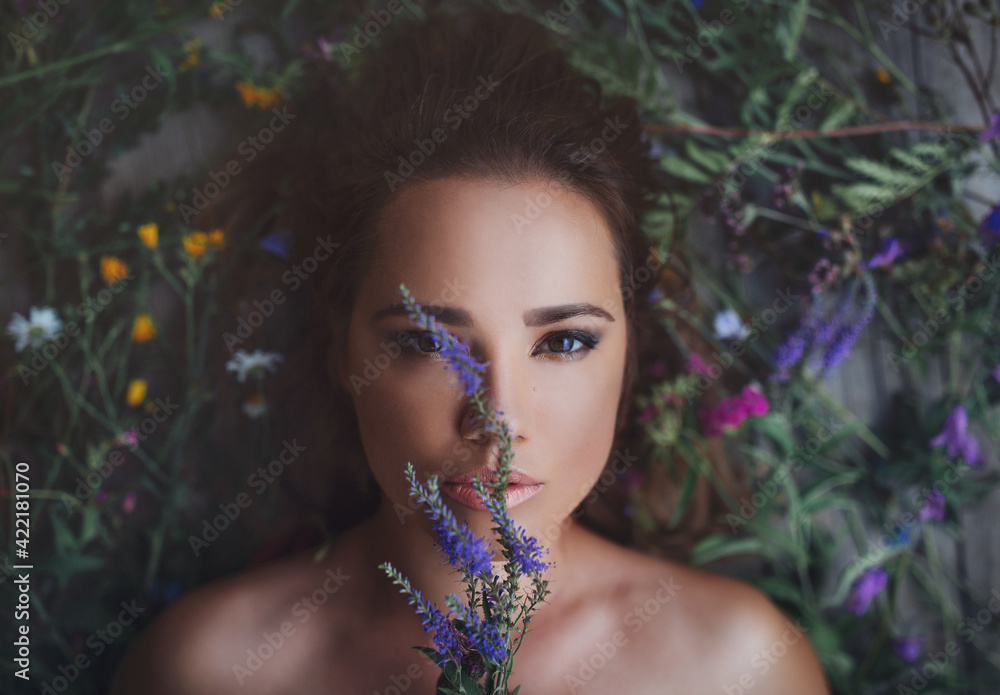 Beauty close up portrait of stunning girl lying on wildflowers with flowers around her head. View from above. Looking  mysteriously. Concept of spring summer youth beauty.  Beautiful face. Romantic - obrazy, fototapety, plakaty 