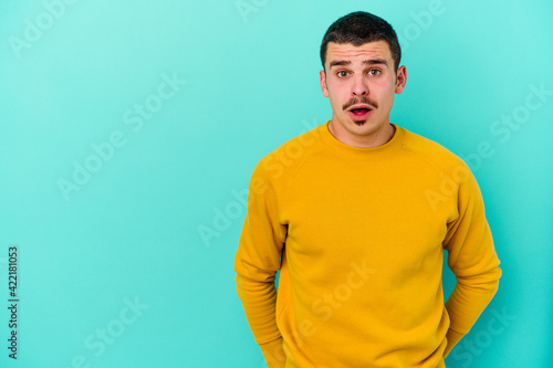 Young caucasian man isolated on blue background being shocked because of something she has seen.