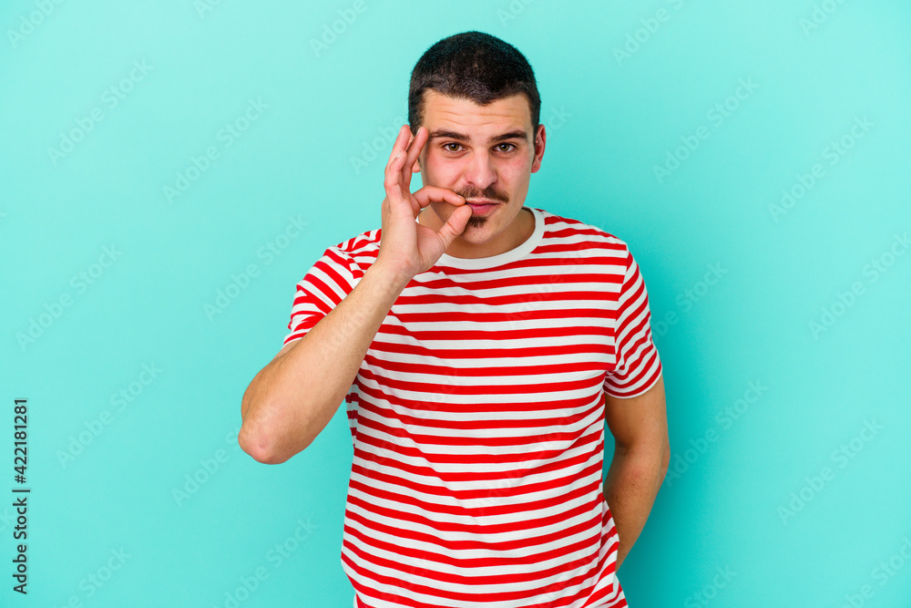Young caucasian man isolated on blue background with fingers on lips keeping a secret. Young caucasian man isolated on blue background with fingers on lips keeping a secret.