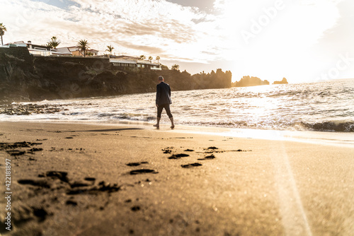 Business man walking on the beach at sunset light. Freedom.