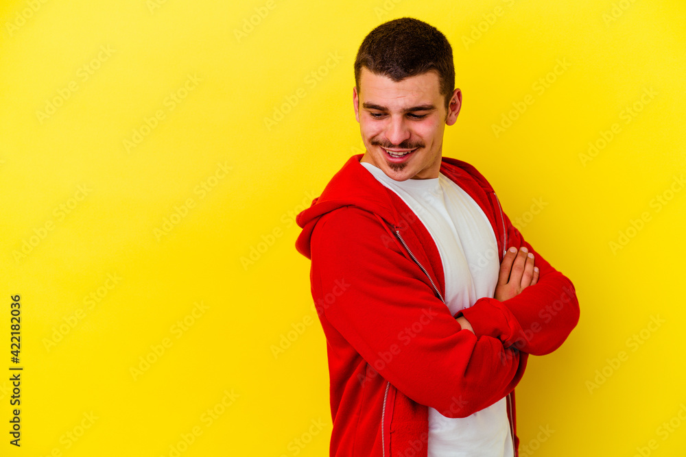 Young caucasian cool man isolated on yellow background smiling confident with crossed arms. Young caucasian cool man isolated on yellow background smiling confident with crossed arms.