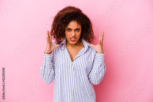 Young african american woman isolated on pink background screaming with rage.