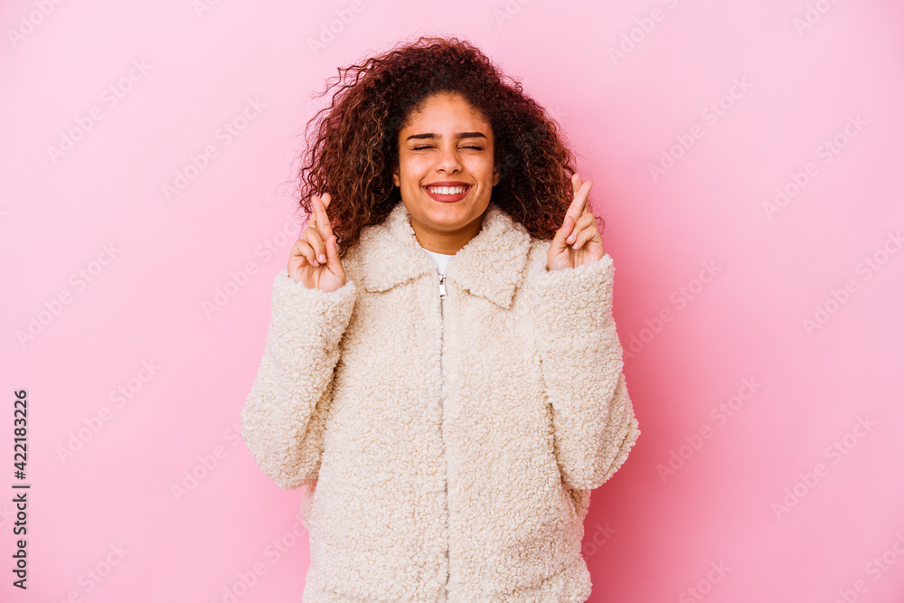 Young african american woman isolated on pink background crossing fingers for having luck