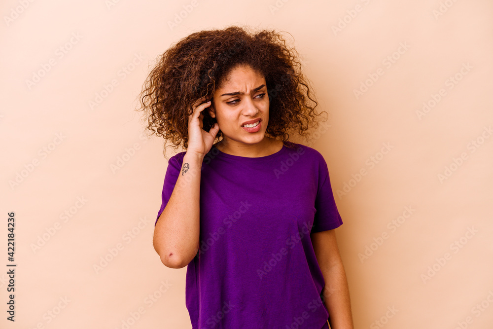 Young african american woman isolated on beige background covering ears with hands. Young african american woman isolated on beige background covering ears with hands.