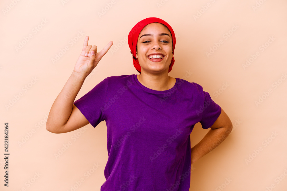 Naklejka premium Young african american woman isolated on beige background showing rock gesture with fingers