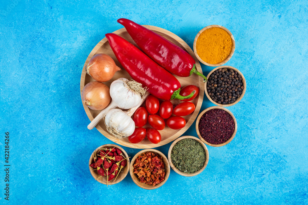 Plate of vegetables and spices on blue background