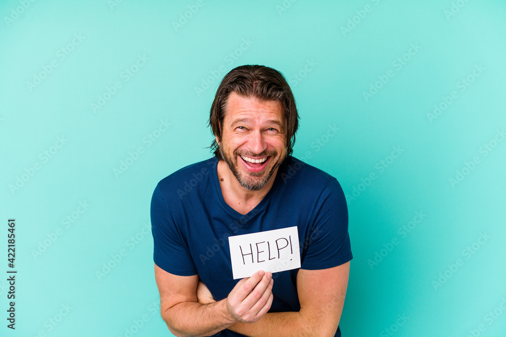 Middle age dutch man holding a help placard isolated on blue background laughing and having fun. Middle age dutch man holding a help placard isolated on blue background laughing and having fun.