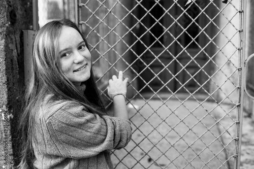 Cute teengirl near the fence on the city street. Black and white photo. © De Visu