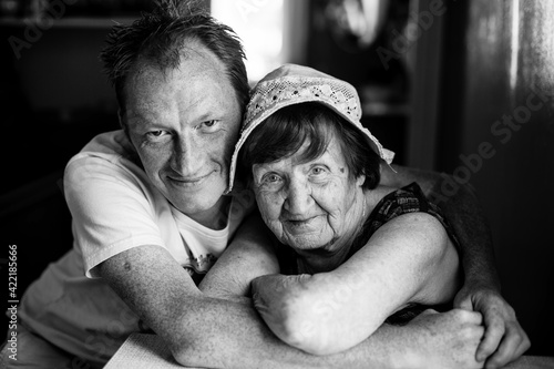 Portrait of old woman with her adult grandson. Black and white photo.