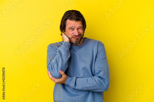 Middle age caucasian man isolated on yellow background massaging elbow, suffering after a bad movement.