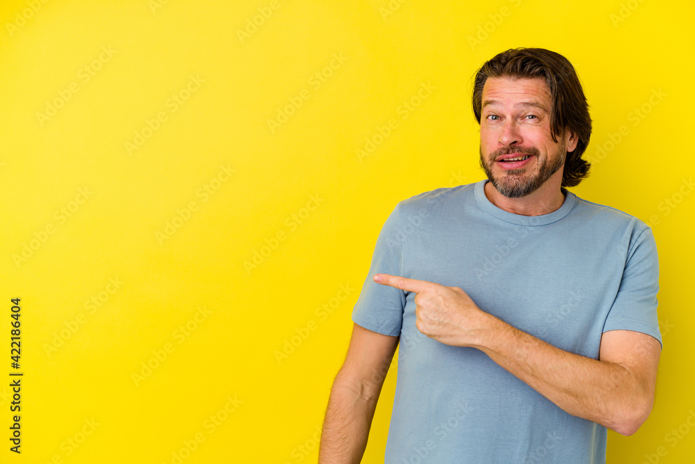 Middle age caucasian man isolated on yellow background smiling and pointing aside, showing something at blank space. Middle age caucasian man isolated on yellow background smiling and pointing aside, showing something at blank space.
