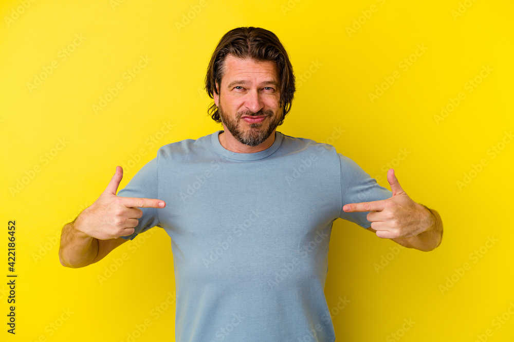 Middle age caucasian man isolated on yellow background points down with fingers, positive feeling. Middle age caucasian man isolated on yellow background points down with fingers, positive feeling.