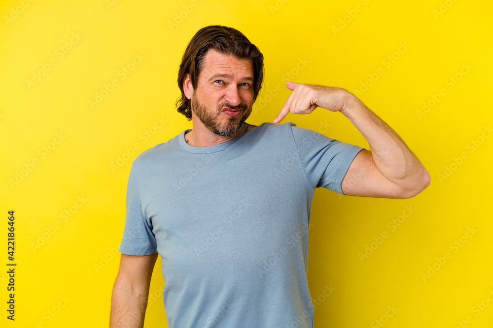 Middle age caucasian man isolated on yellow background person pointing by hand to a shirt copy space, proud and confident Middle age caucasian man isolated on yellow background person pointing by hand to a shirt copy space, proud and confident