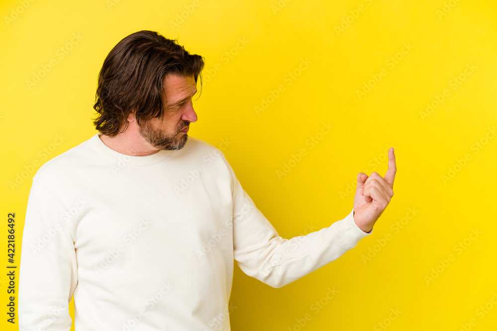 Middle age caucasian man isolated on yellow background pointing with finger at you as if inviting come closer. Middle age caucasian man isolated on yellow background pointing with finger at you as if inviting come closer.