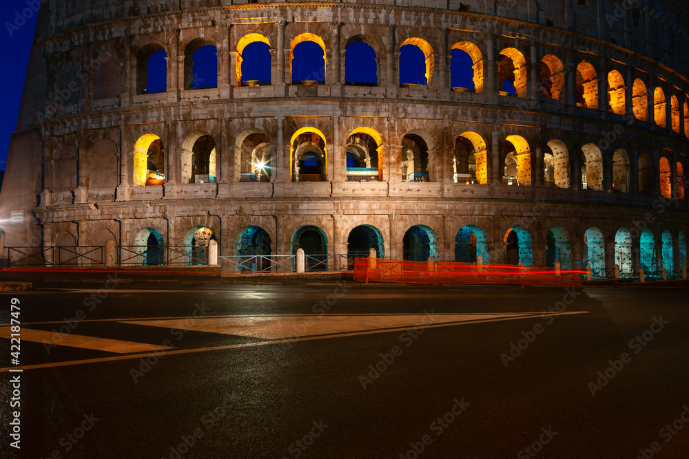 Fototapeta premium No people on the street near Colosseum in Rome . Famous architecture illuminated in the night . Empty italian street 
