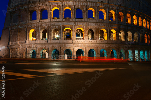 No people on the street near Colosseum in Rome . Famous architecture illuminated in the night . Empty italian street 
