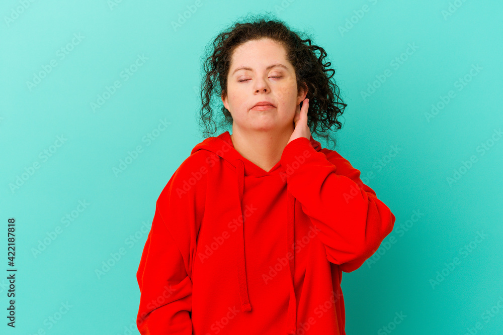 Fototapeta premium Woman with Down syndrome isolated having a neck pain due to stress, massaging and touching it with hand.
