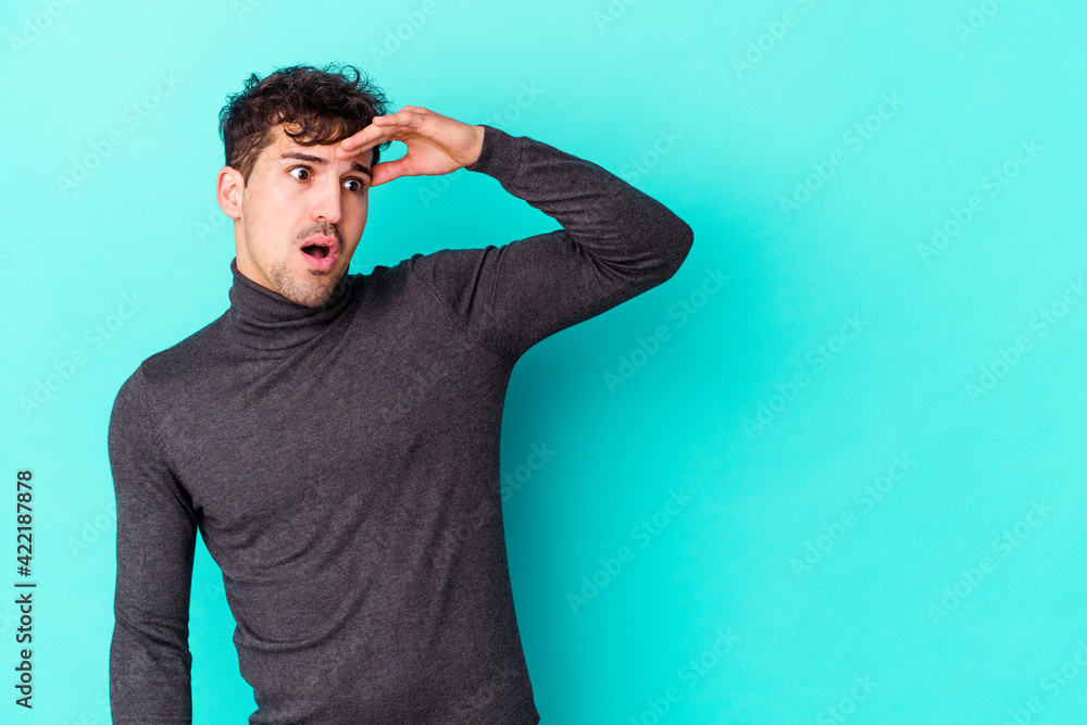 Young caucasian man isolated on blue background looking far away keeping hand on forehead. Young caucasian man isolated on blue background looking far away keeping hand on forehead.