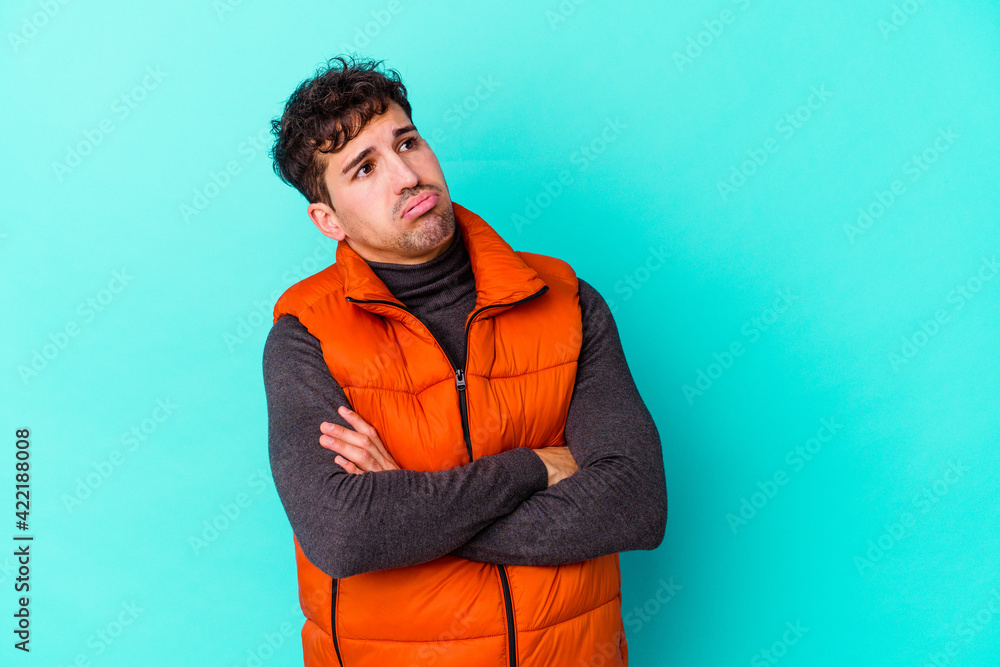 Young caucasian man isolated on blue background tired of a repetitive task. Young caucasian man isolated on blue background tired of a repetitive task.