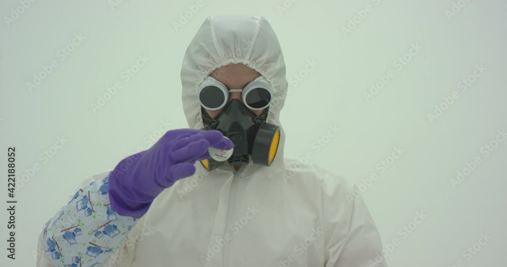 Man in white chemical protection suit and gas mask releases a ping-pong ball, which hovers in front of him with help of hot air from the hair dryer. Close up camera, slow motion Man in white chemical protection suit and gas mask releases a ping-pong ball, which hovers in front of him with help of hot air from the hair dryer. Close up camera, slow motion
