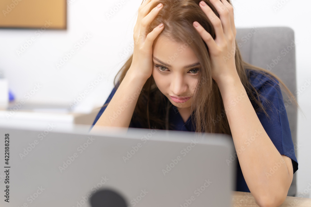 Portrait of business woman working while using a laptop on some reports from home while he is tired and stressed. Business woman multitasking and stress.