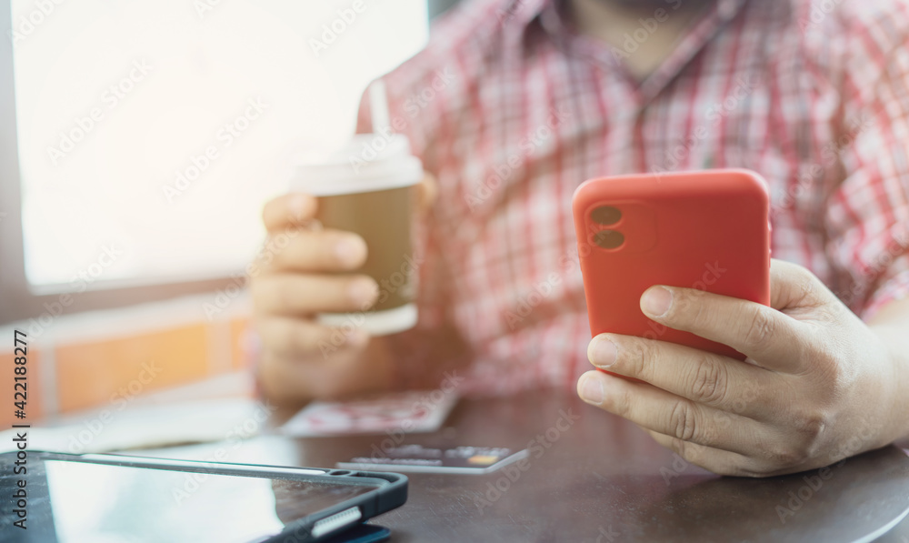 close-up hands holding coffee paper cup and smartphone while sitting at coffee shop. Businessman drinking coffee and smiling. Freelancer working and checking email and chatting with customer. trader close-up hands holding coffee paper cup and smartphone while sitting at coffee shop. Businessman drinking coffee and smiling. Freelancer working and checking email and chatting with customer. trader