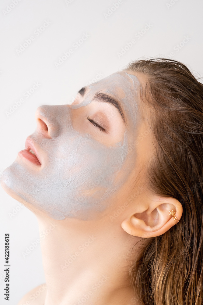 Facial skin care. Organic cosmetics. Spa therapy. Profile portrait of relaxed woman with blue clay mask on face isolated on light neutral background. Facial skin care. Organic cosmetics. Spa therapy. Profile portrait of relaxed woman with blue clay mask on face isolated on light neutral background.