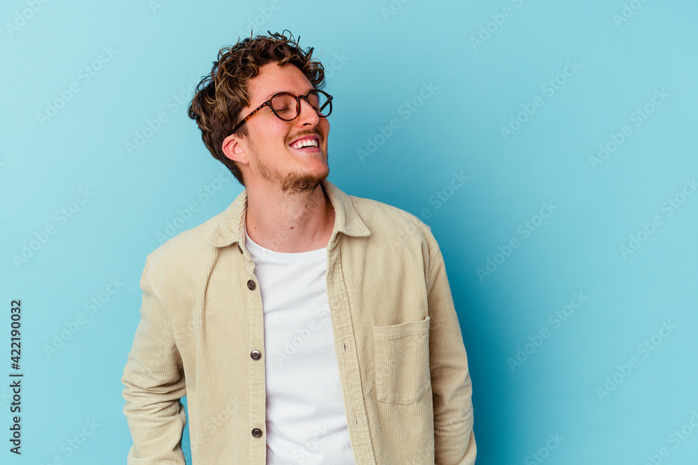 Fototapeta premium Young caucasian man wearing eyeglasses isolated on blue background relaxed and happy laughing, neck stretched showing teeth.
