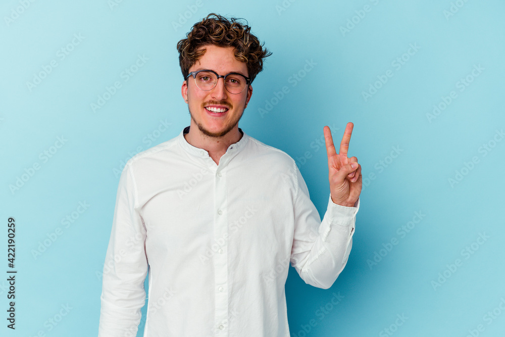 Fototapeta premium Young caucasian business man isolated on blue background showing victory sign and smiling broadly.