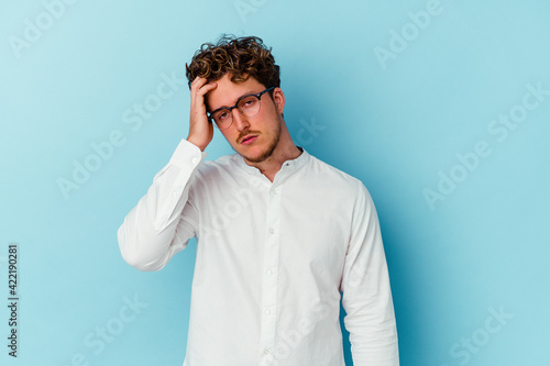 Young caucasian business man isolated on blue background being shocked, she has remembered important meeting. © Asier