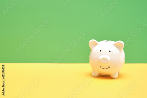 White piggy bank on green and yellow background. Saving money wealth and financial concept