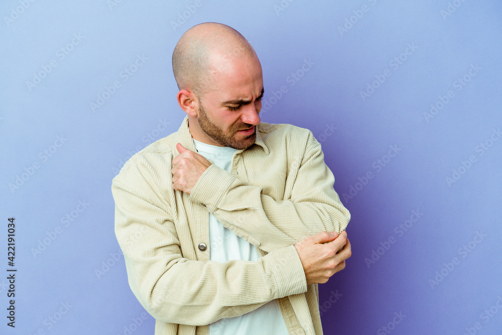 Fototapeta premium Young caucasian bald man isolated on purple background massaging elbow, suffering after a bad movement.