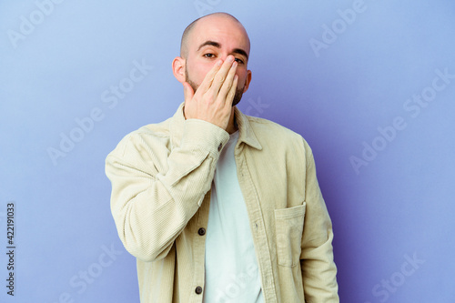 Young caucasian bald man isolated on purple background shocked, covering mouth with hands, anxious to discover something new. photo