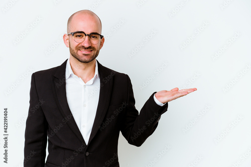 Young business caucasian bald man isolated on white background showing a copy space on a palm and holding another hand on waist. Young business caucasian bald man isolated on white background showing a copy space on a palm and holding another hand on waist.